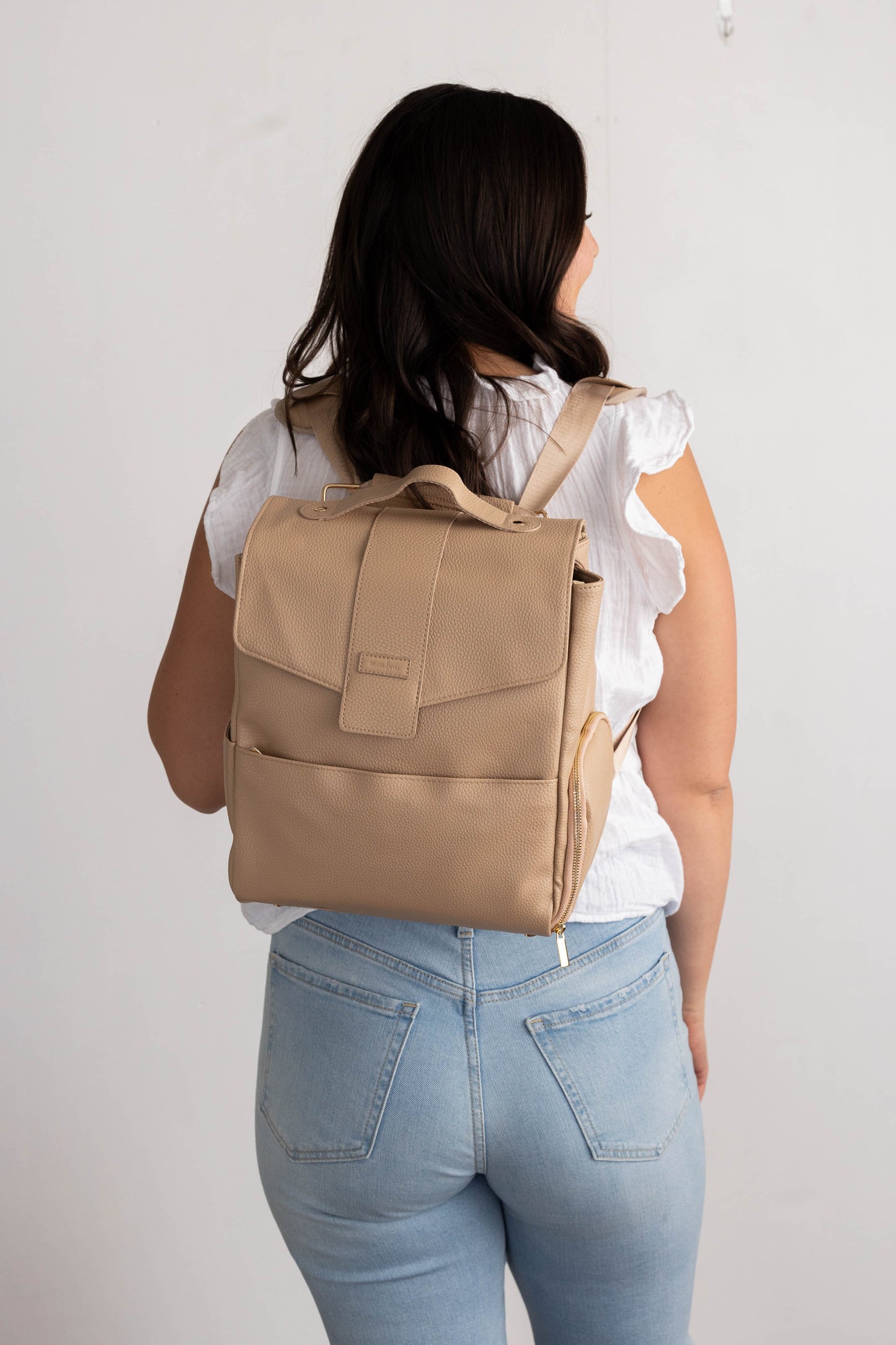 Image of a woman wearing Hallie Mini Breast Pump Bag as a backpack (shown with a view of backpack front)